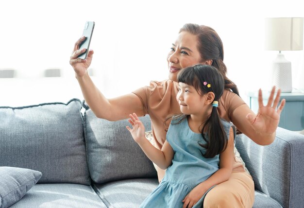 Asian grandmother happy using smartphone taking a selfie photo granddaughter together