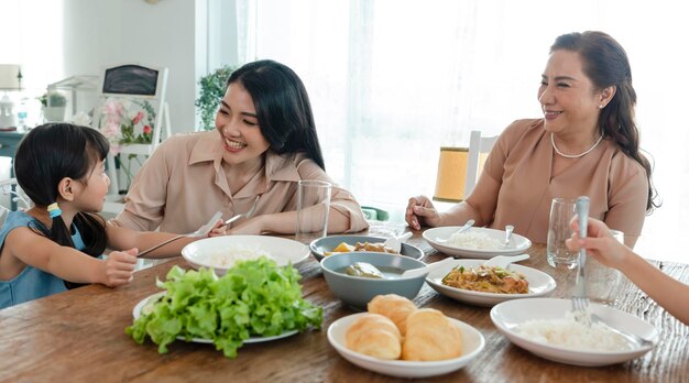 アジアの幸せな家族は、家の中で関係と活動を一緒にテーブルで昼食をとる時間を過ごします