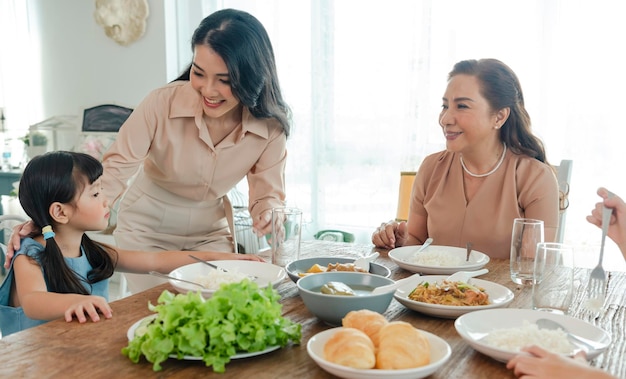 Азиатская счастливая семья проводит время, обедая за столом вместе, отношения и активность в доме