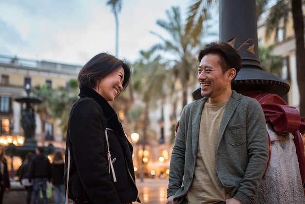 Asian happy tourist couple talking in a square