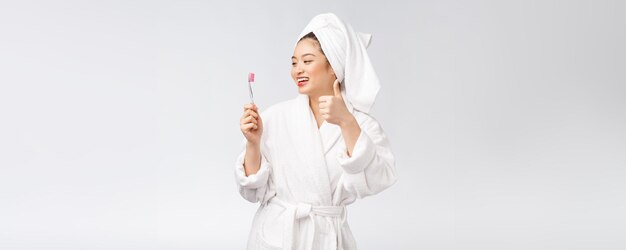 Asian happy woman with toothbrush in bathrobe morning mood