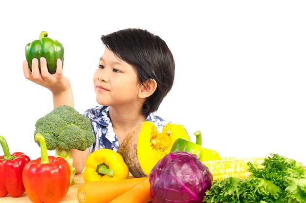 アジアの健康的な少年の様々な新鮮なカラフルな野菜と幸せな表情を示す