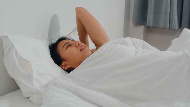 Бесплатное фото Азиатская индийская дама спит в комнате дома. молодая азиатская девушка чувствует себя счастливым расслабиться отдыхать лежа на кровати, чувствовать себя комфортно и спокойно в спальне в доме на утро.