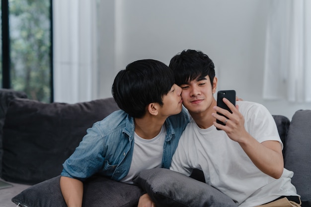 アジア​の​インフルエンサーゲイカップル​の​ビデオブログ​を​自宅​で​。​アジア​の​lgbtq​の​男性​は​、​リビング​ルーム​の​ソファ​に​横たわっている​間​、​ソーシャルメディア​で​技術​携帯​電話​記録​ライフスタイルビデオアップロード​を​使用して​楽しい​リラックス​を​楽しんでいます​。