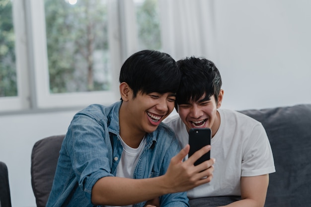 アジア​の​インフルエンサーゲイカップル​の​ビデオブログ​を​自宅​で​。​アジア​の​lgbtq​の​男性​は​、​リビング​ルーム​の​ソファ​に​横たわっている​間​、​ソーシャルメディア​で​技術​携帯​電話​記録​ライフスタイルビデオアップロード​を​使用して​楽しい​リラックス​を​楽しんでいます​。