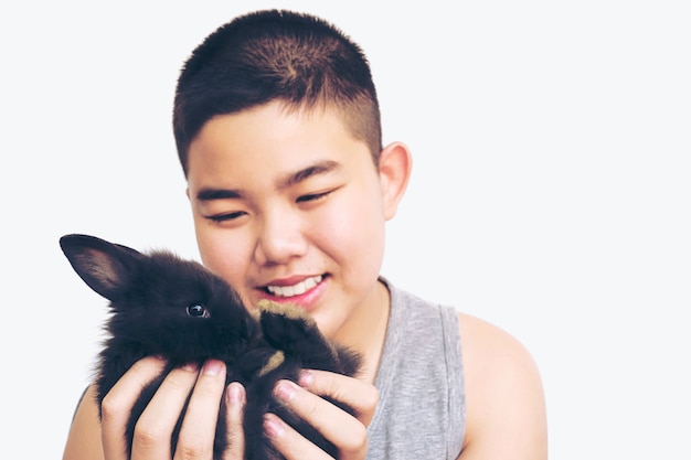 Азиатский малыш играет с прекрасным кроликом