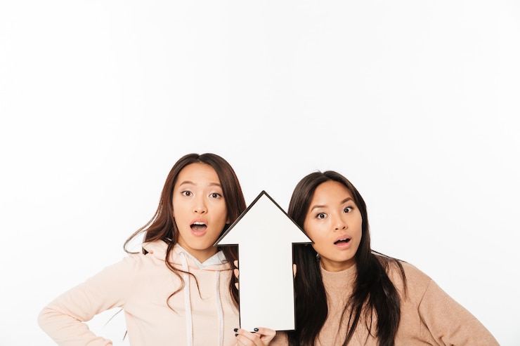 無料Photo アジアの女性の姉妹が矢印を保持しています。
