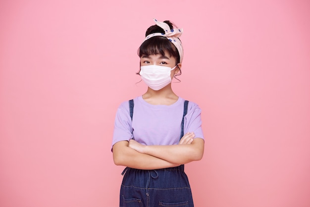무료 사진 분홍색 벽에 고립 된 바이러스 covid-19로부터 그녀를 보호하기 위해 마스크를 쓰고 아시아 소녀.