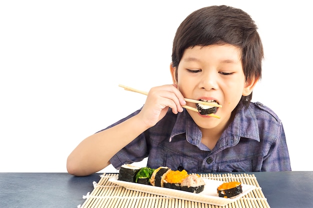 アジアの素敵な男の子は白い背景で隔離の寿司を食べています。