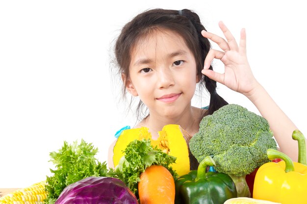 アジアの素敵な女の子を示す新鮮なカラフルな野菜の表現を楽しむ