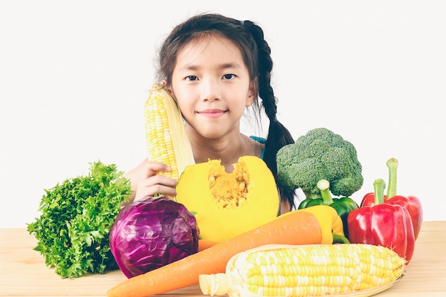 アジアの素敵な女の子を示す新鮮なカラフルな野菜の表現を楽しむ