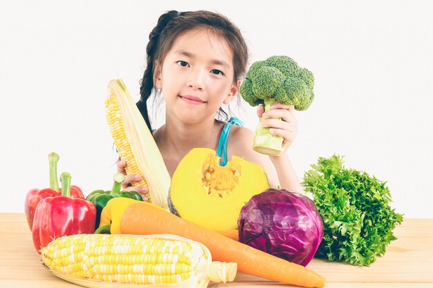 アジアの素敵な女の子を示す新鮮なカラフルな野菜の表現を楽しむ