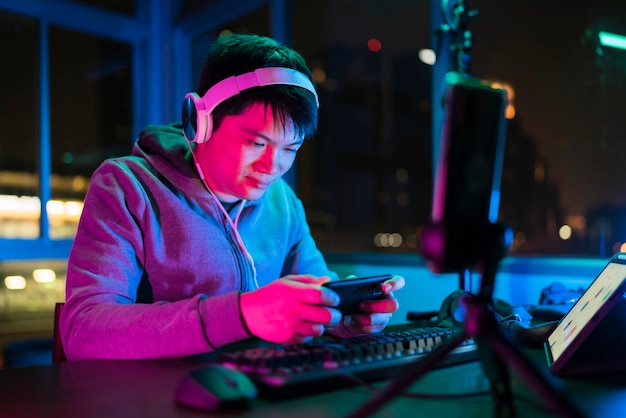 Азиатский киберспортсмен-мужчина, играющий в многопользовательскую онлайн-игру спортивных лиг через смартфон с взволнованными и веселыми эмоциями