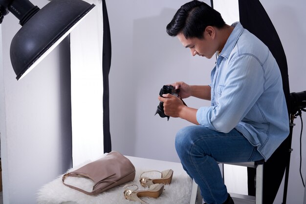 스튜디오에 앉아 패션 액세서리 사진을 찍는 아시아 남성 사진 작가