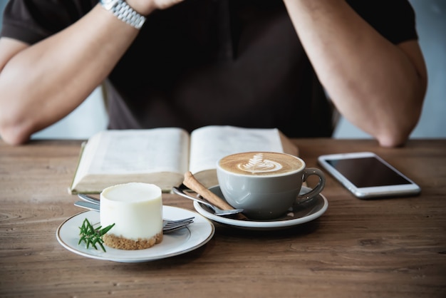 アジア人の男性がコーヒーを飲むと本を読んで