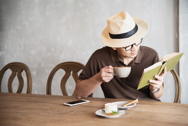 アジア人の男性がコーヒーを飲むと本を読んで