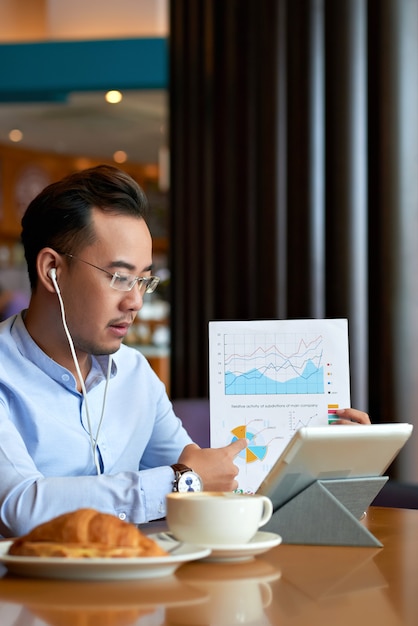 Asian man explaining data in business document to his business partner on a video call