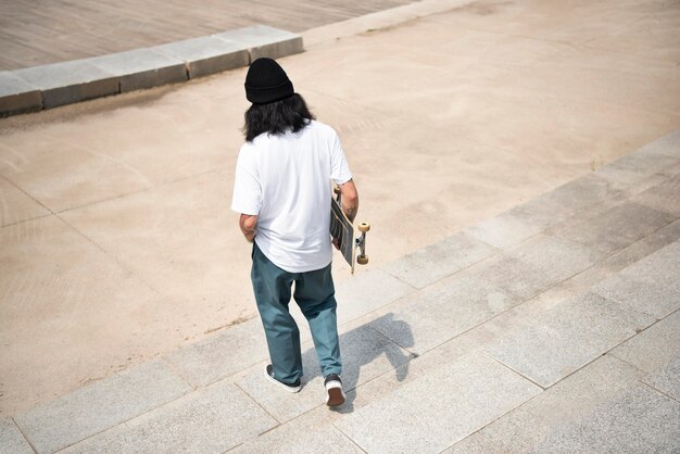Asian man holding his skateboard