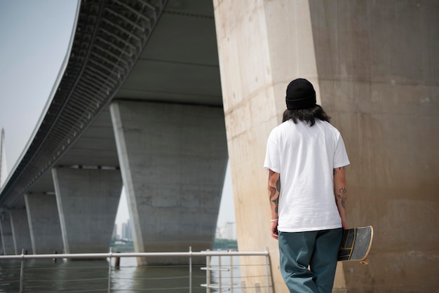 Free photo asian man holding his skateboard