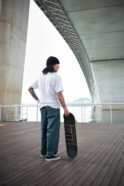 Азиатский мужчина держит скейтборд