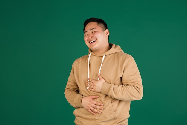 Free photo asian man's portrait isolated over green studio background with copyspace