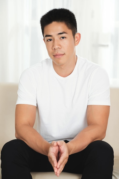 Asian man sitting on couch at home 