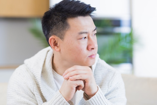 Premium Photo | Asian man sitting on sofa at home pensive worried about  problems and depression