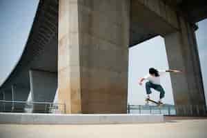 Free photo asian man skateboarding in the city outdoors