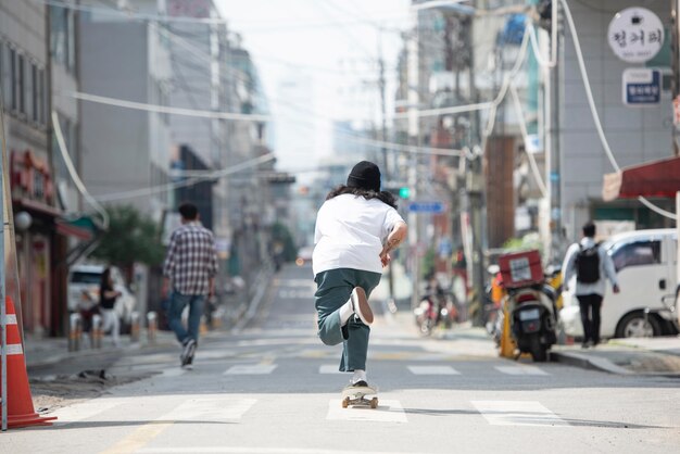 Азиатский мужчина катается на скейтборде на открытом воздухе