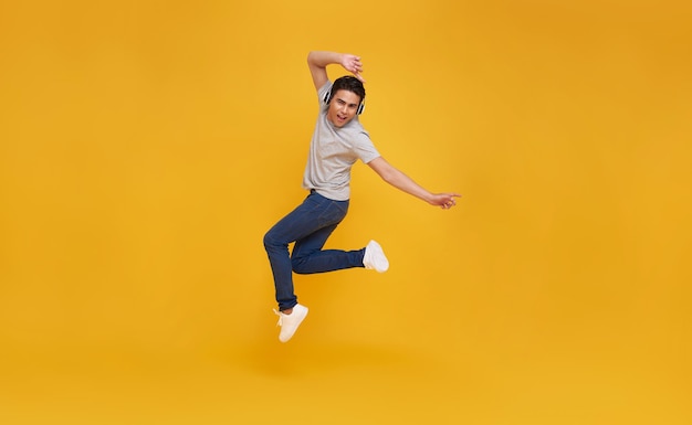 Free photo asian man smiling and jumping wearing wireless headphone listening to music