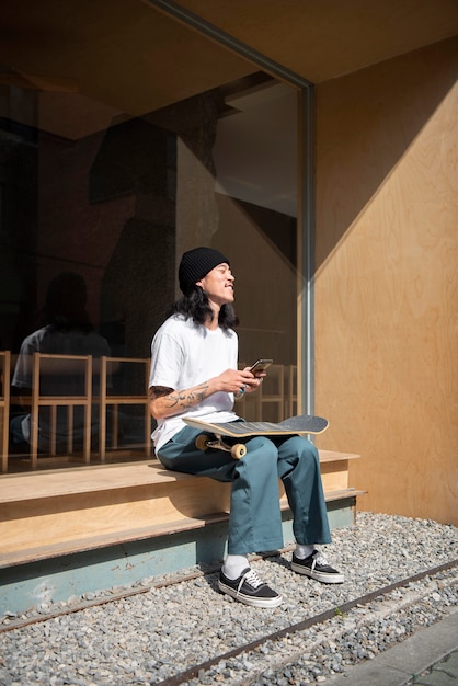 Foto gratuita uomo asiatico che si prende una pausa dallo skateboard