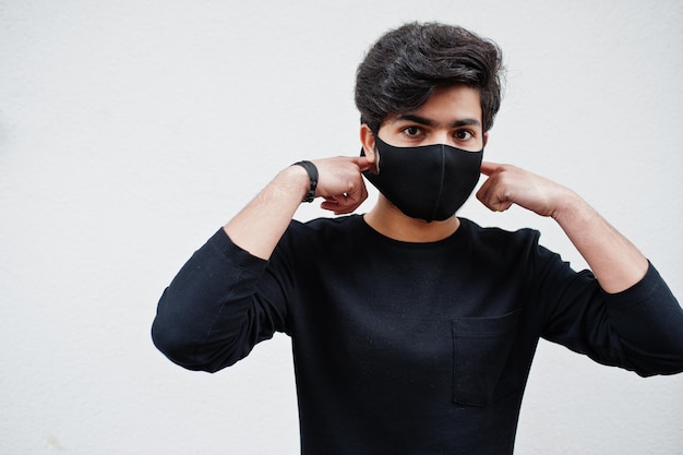 アジア人男性は白い背景で隔離のフェイスマスクですべて黒を着用します