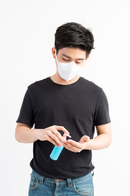 検疫室でコロナウイルスcovid-19を保護するために手を洗うためのアルコールを保持しているフェイスマスクを身に着けているアジア人男性