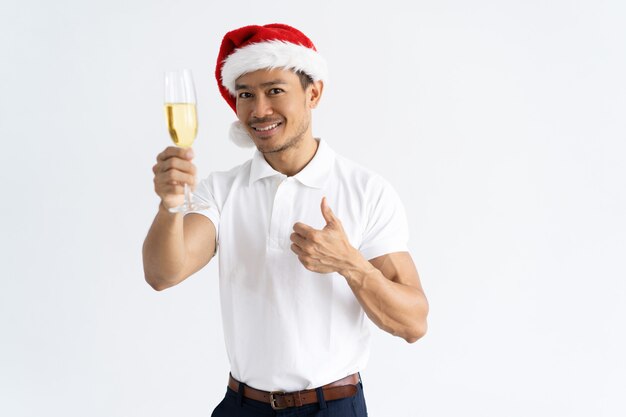 Asian man wearing Santa hat and raising goblet with champagne