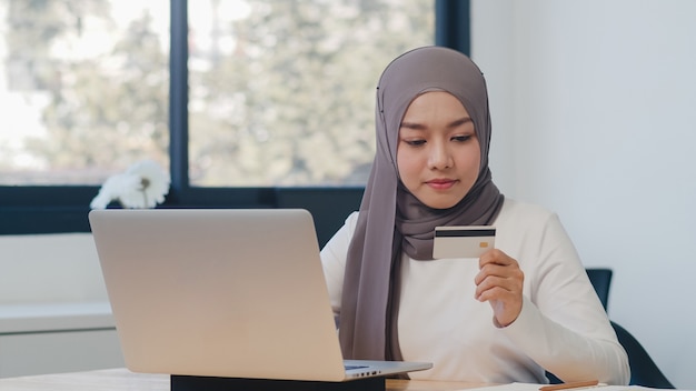 Asian muslim lady using laptop, credit card buy and purchase e-commerce internet in office.