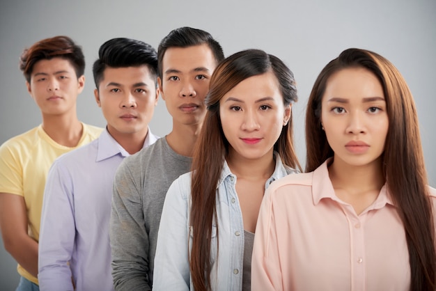 Free photo asian people standing in a rowlooking at camera