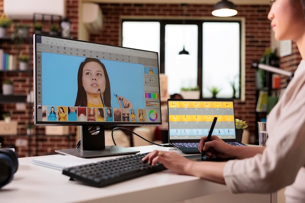 Free photo asian photographer editing picture with retouching software on computer. working with retoucher interface to edit art photograph with color grading and visual contrast, multimedia production.