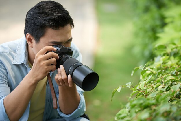 Asian photographer taking macro photos of green leaves