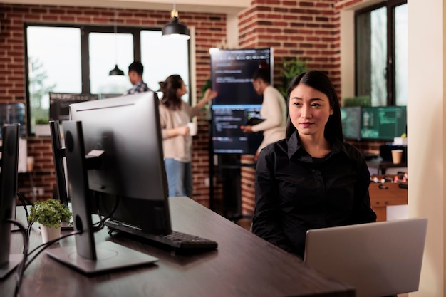 Free photo asian programmer typing machine learning server code, sitting at desk table in it software company. programming engineer working on database system with coding script in it developing office