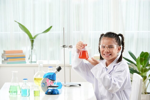 화학 연구를 하 고 안경 및 흰색 실험실 가운을 입고 아시아여 학생