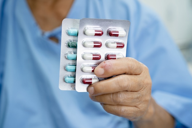 ブリ​スター​に​抗生​物質​カプセル​錠剤​を​保持している​アジア​の​年配​の​女性​患者