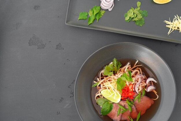 Asian soup ramen with pork and noodles iserved on gray background