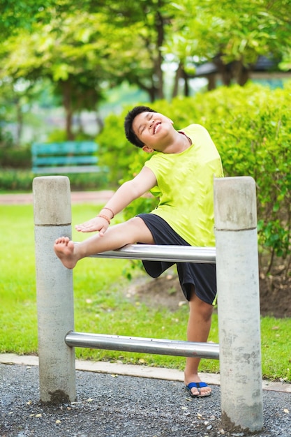 Asian sport boy stretching on iron bar in garden