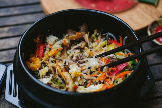 Asian street food in black plastic plate with chopsticks