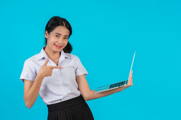 An Asian student girl holding her notebook on a blue .