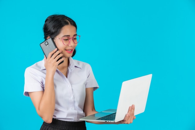 An Asian student girl holding her notebook on a blue .