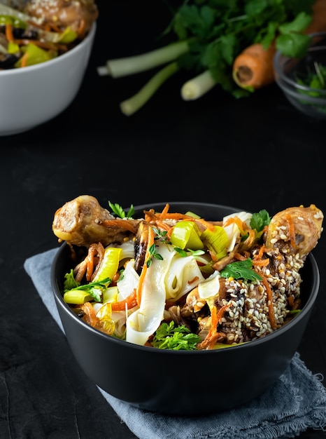 Asian-style lunch with noodles with chicken in teriyaki sauce, vegetables, spices and microgreens