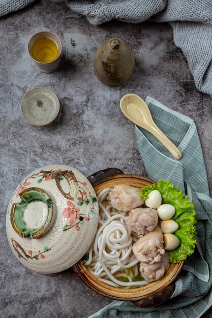 テーブルの上のボウルに麺、豚肉、ねぎのアジア風スープ。