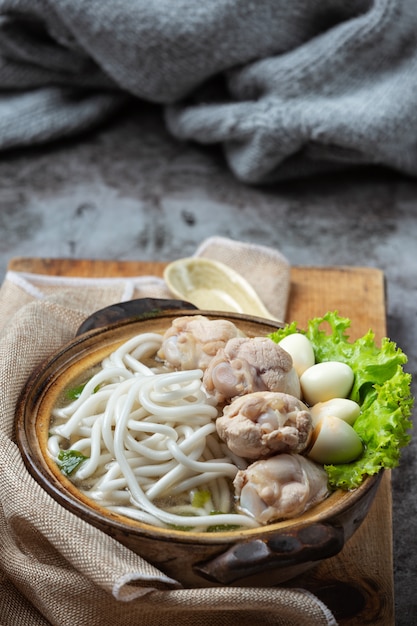 テーブルの上のボウルに麺、豚肉、ねぎのアジア風スープ。