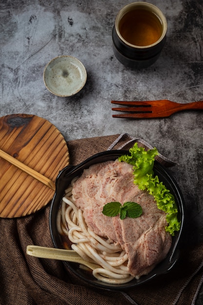 Asian style soup with noodles, pork and green onions closely in a bowl on the table.